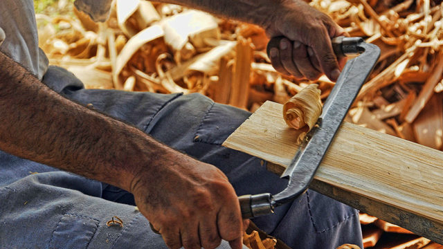 A man scraping a piece of wood