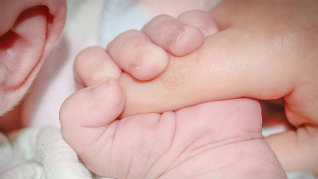 Baby holding mom's finger